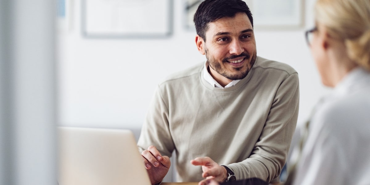 man in the office, speaking to colleague