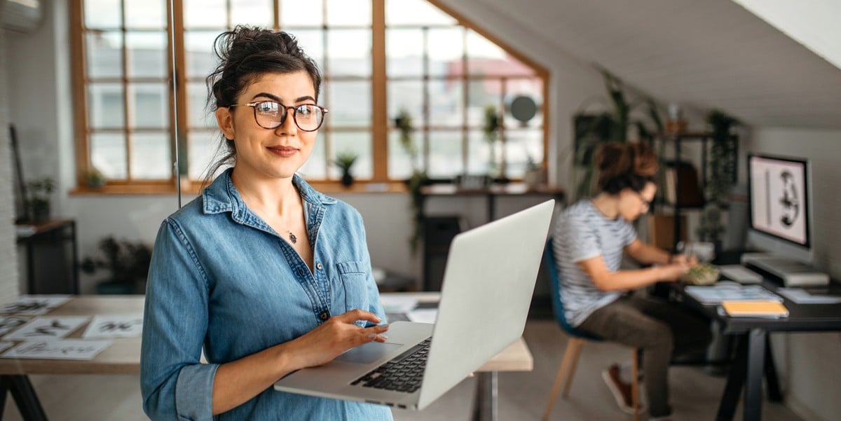 professional woman smiling, holding laptop
