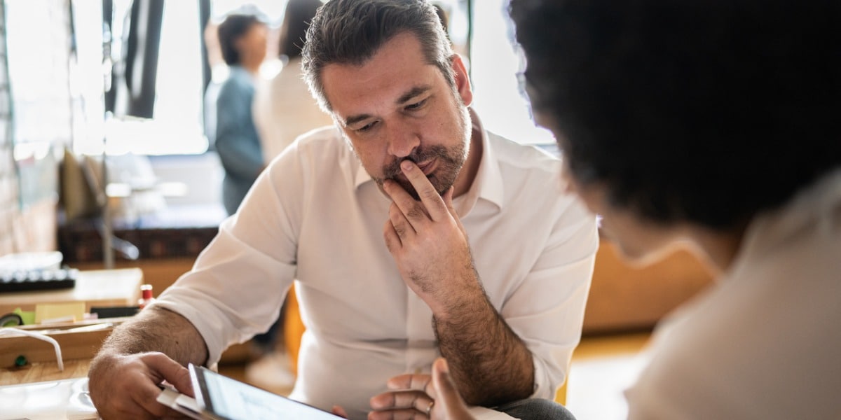 man looking at a tablet with his coworker