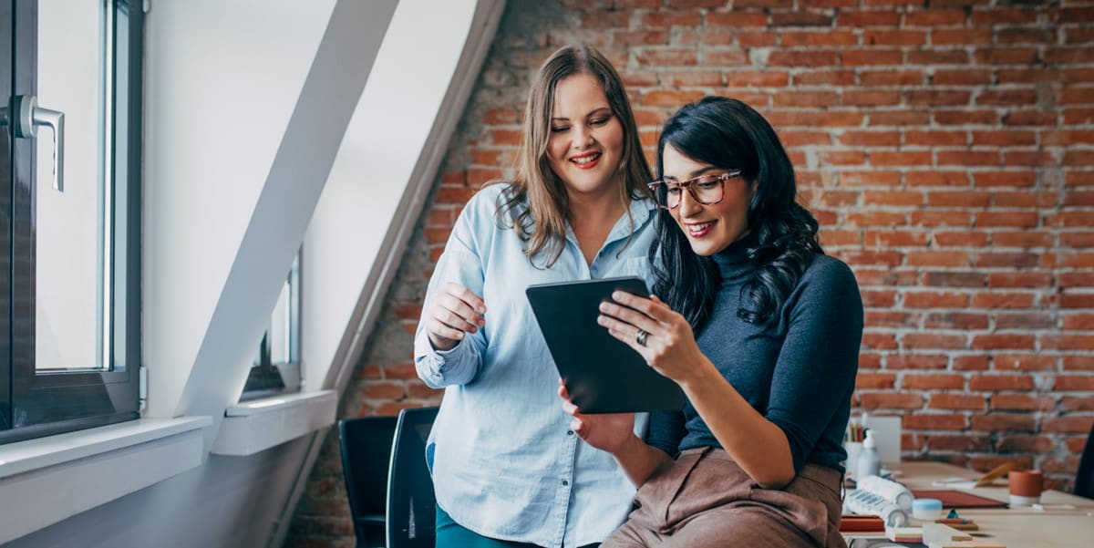 dos mujeres profesionales en oficina revisando documento