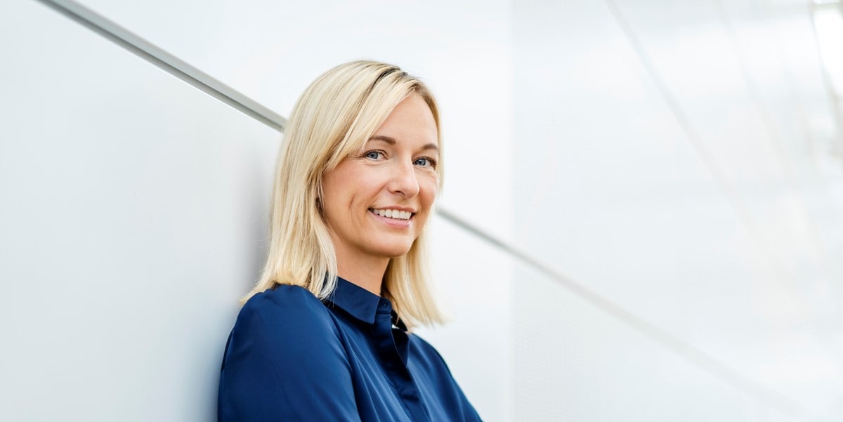 professional woman smiling, leaning against white wall
