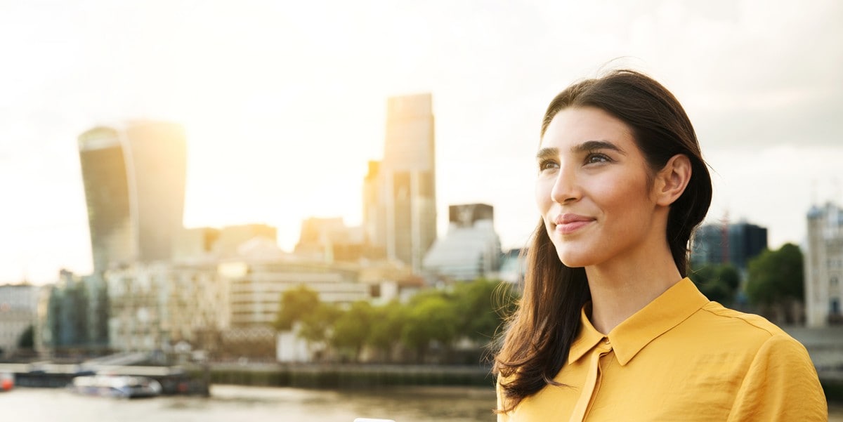 woman smiling, standing outside in front of city skyline