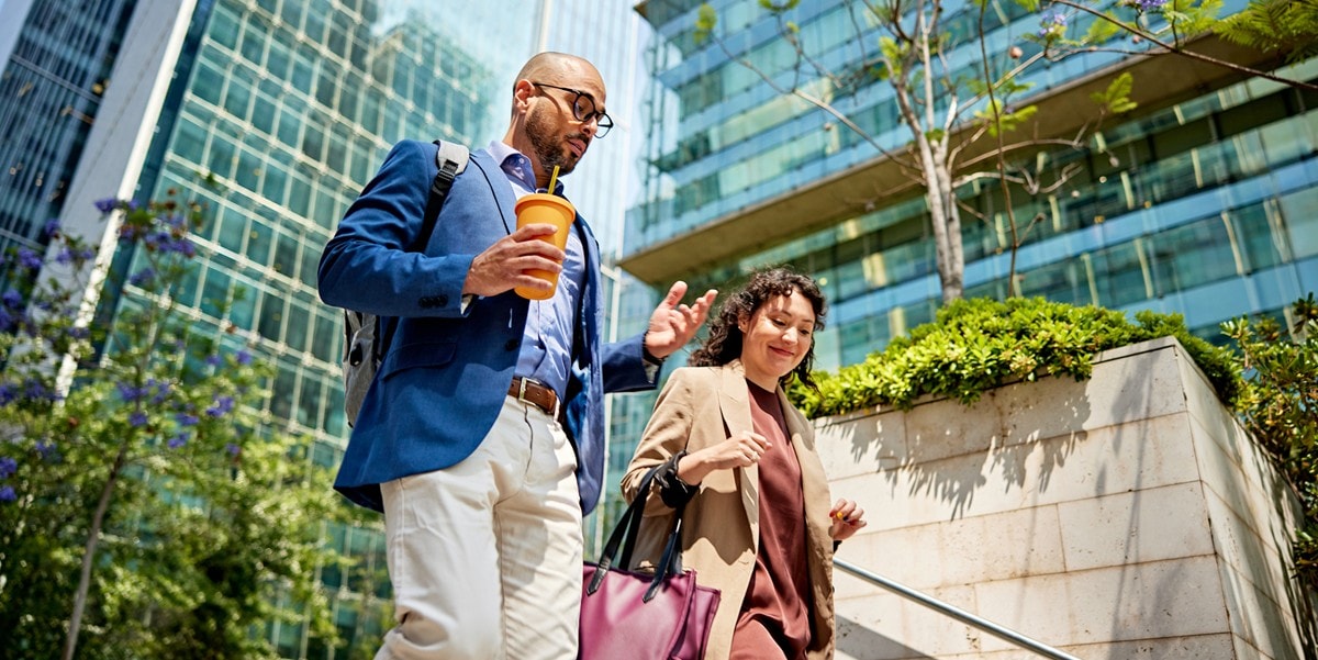 two people walking down stairs, outside, office buildings behind them
