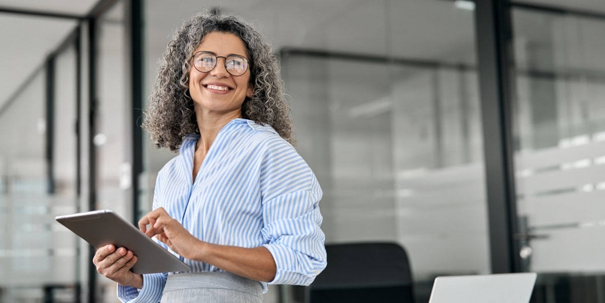 professional woman in the office smiling, holding a tablet