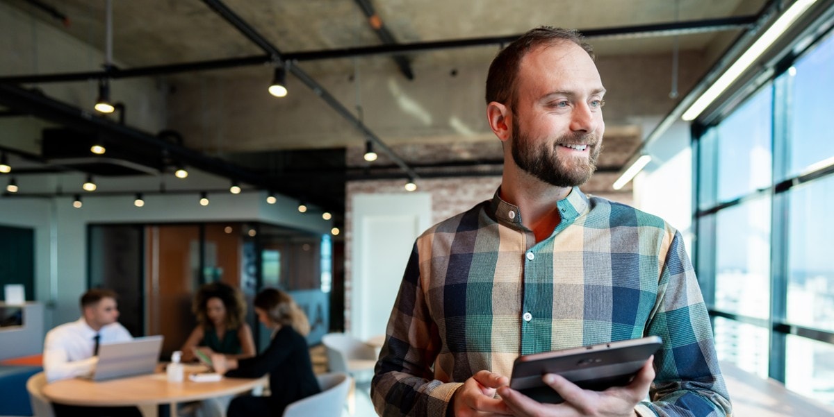 professional man smiling, in the office, holding a tablet