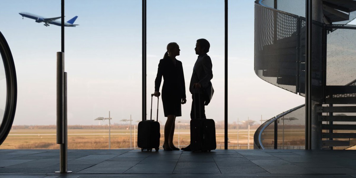 two travelers standing in an airport with luggage