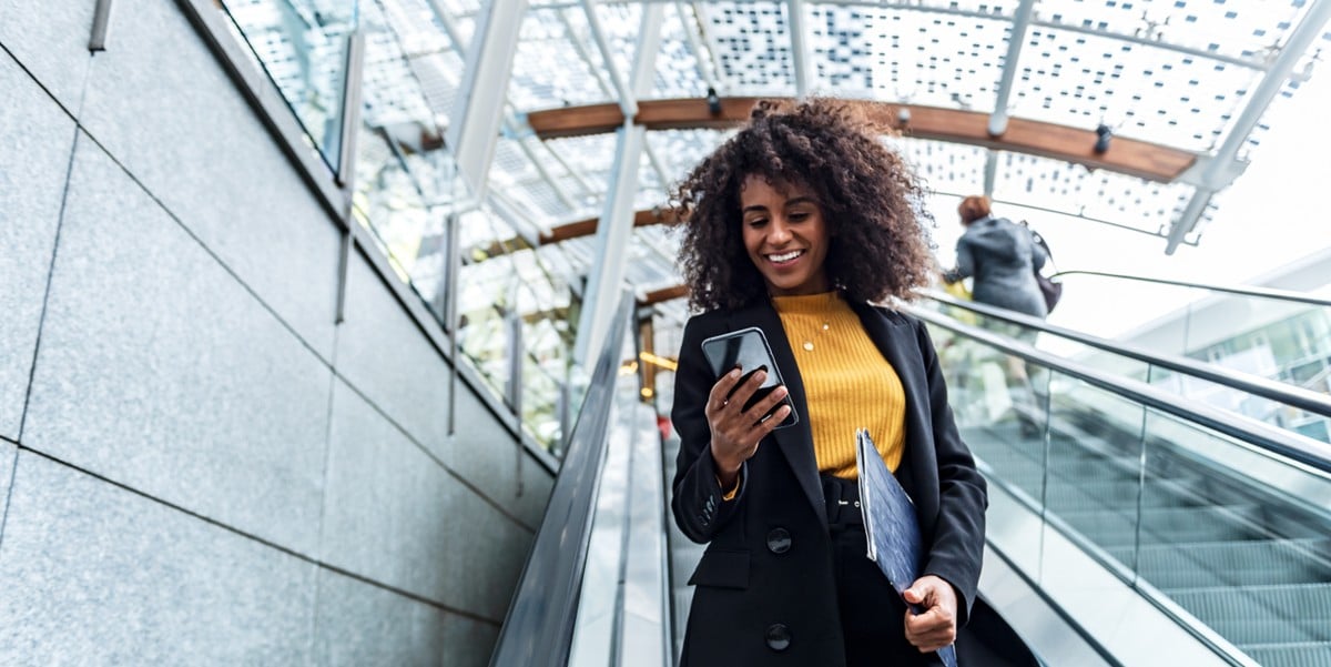 woman traveler on escalator, using cell phone