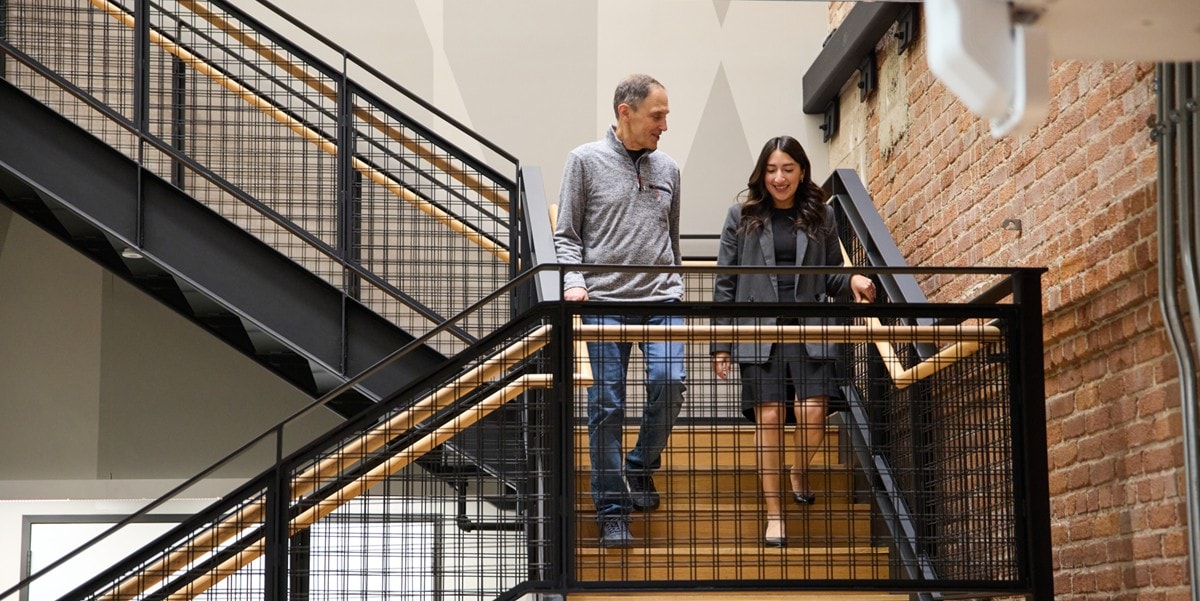 two professionals in an office walking down stairs