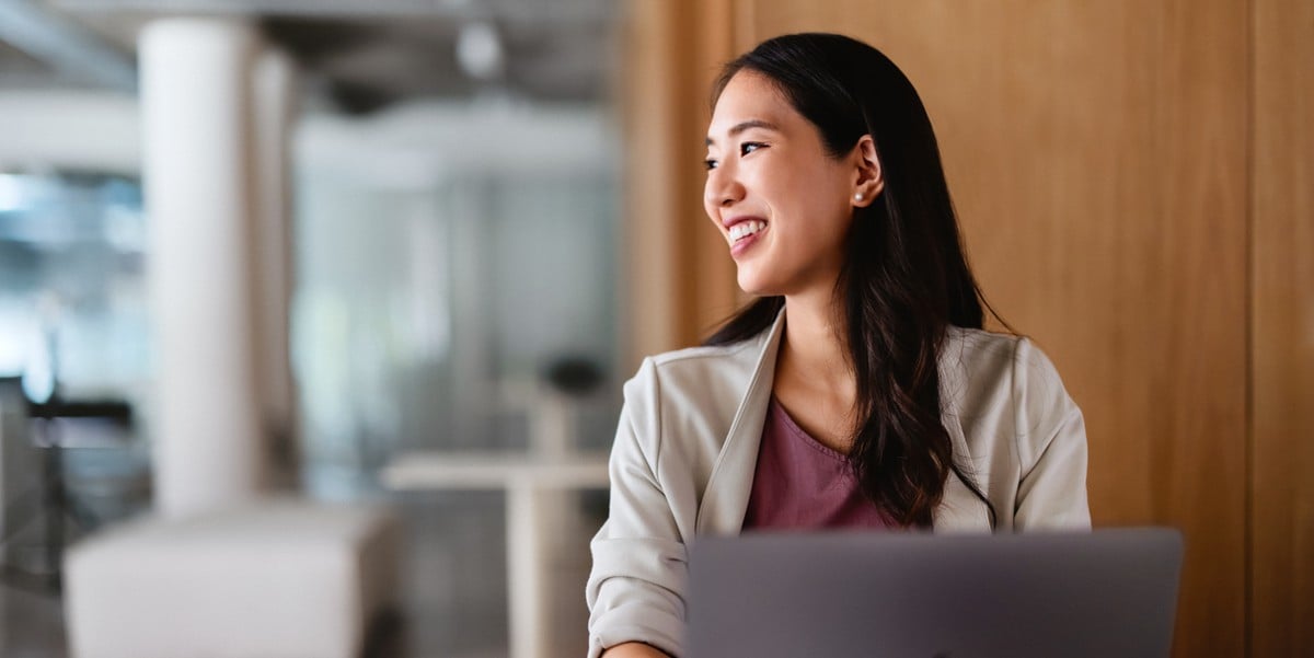 smiling professional woman in the office working at a desk with laptop in front of her