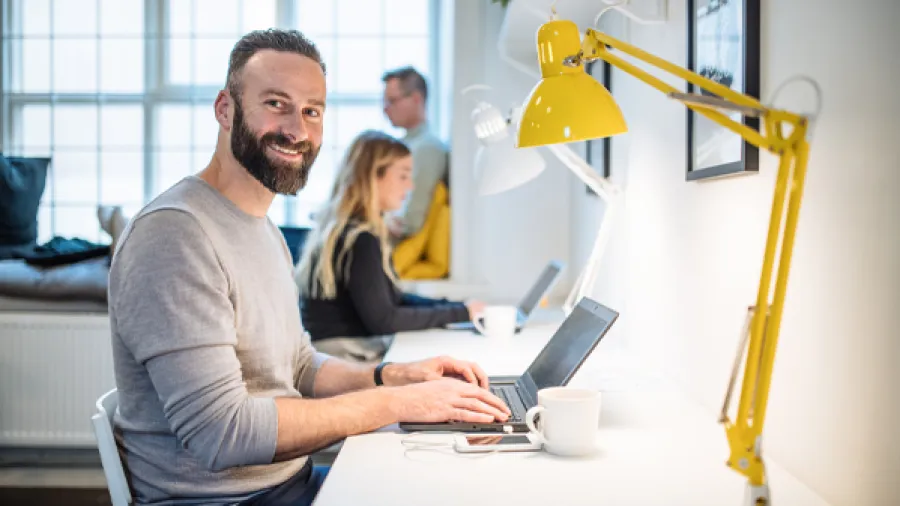 team working at desk with man looking at camera