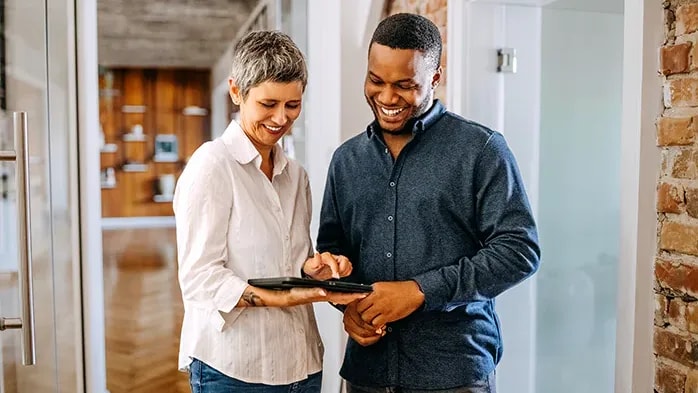 man and woman discussing work on tablet
